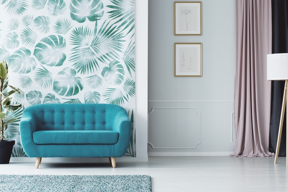 pomysł na ścianę w salonie z roślinną tapetą  pomysł na ścianę w salonie z tapetą i niebieską kanapą