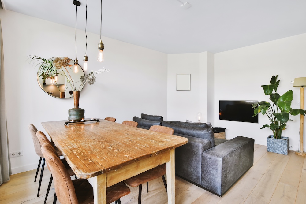 aranżacje salonu z jadalnią z szarą kanapą pod drewnianym stołem 