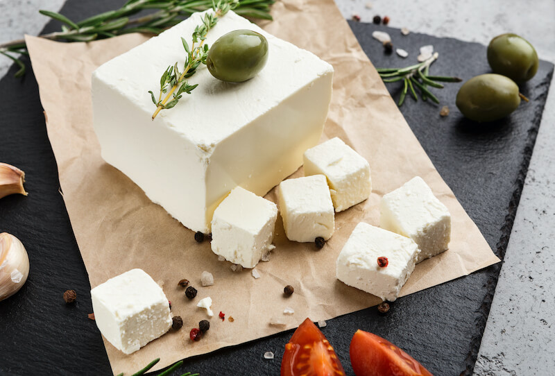 ser feta pokrojony w kostkę obok oliwek ser feta i oliwki zielone