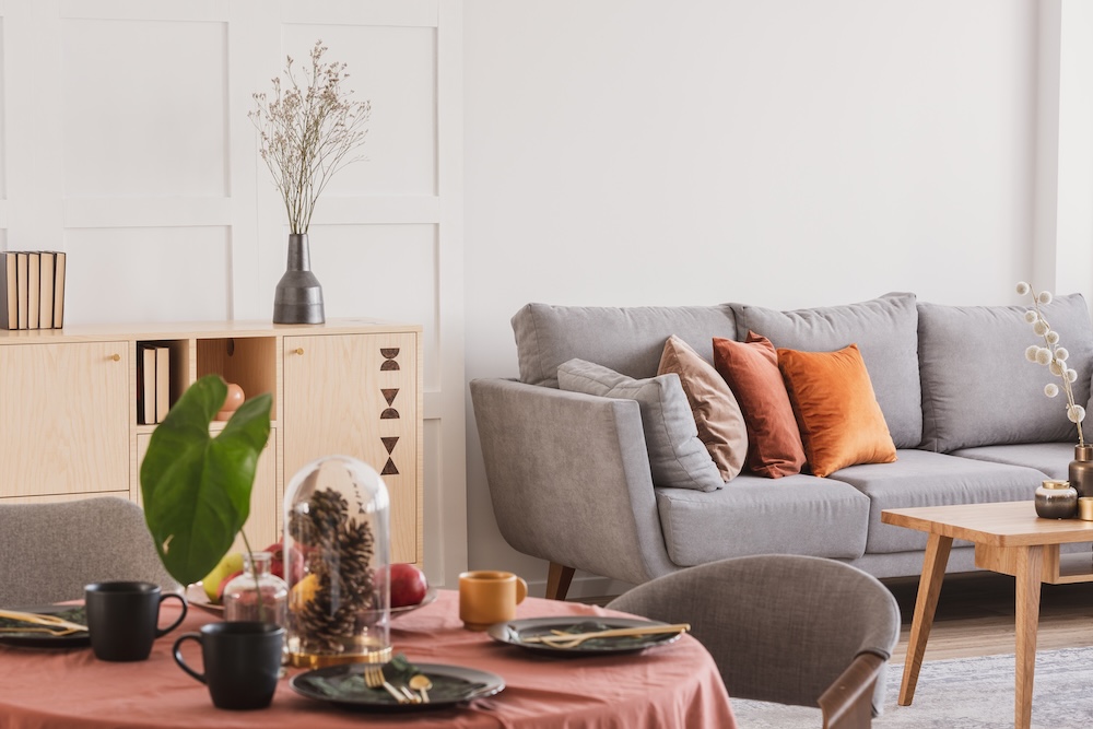 strefa wypoczynkowa z szarą kanapą i jasną komodą 