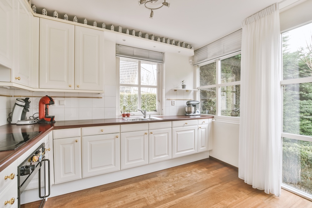 kuchnia z dużym oknem po prawej stronie i jasnymi meblami  kuchnia z białą zabudową i ciemnymi blatami