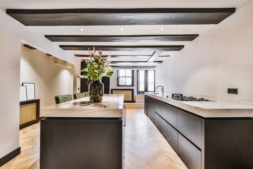 kuchnia z kamiennymi blatami i czarnymi szafkami  długa kuchnia z czarno-białymi meblami i sufitem z drewnem