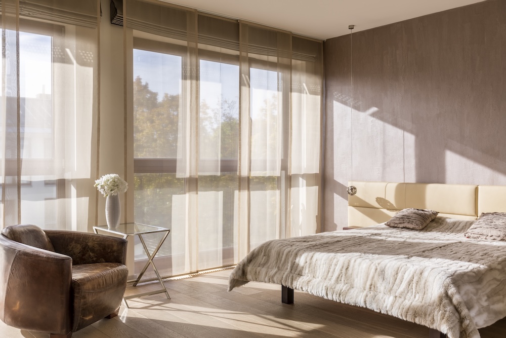 okno w sypialni zasłoniętej beżowymi firankami  okno w sypialni urządzonej w jasnych kolorach