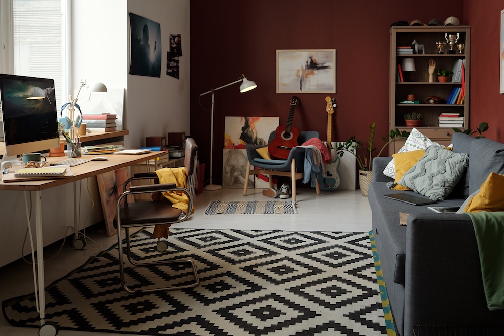 aranżacja kawalerki dwadzieścia siedem m z dywanami na podłodze i szarą sofą na środku  aranżacja kawalerki dwadzieścia siedem m z kanapą i biurkiem pod oknem